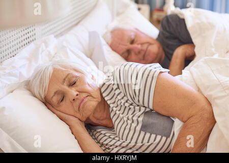 Senior couple asleep in their bed at home Stock Photo