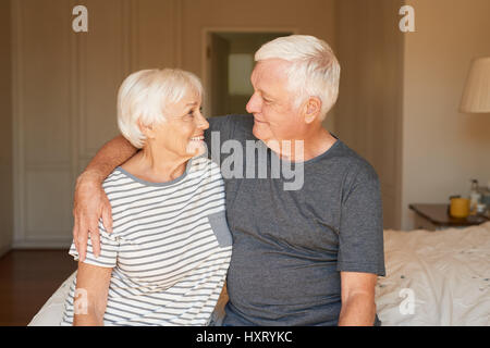 Smiling and affectionate senior couple sitting on their bed together  Stock Photo