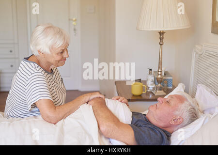 Senior woman taking care of her sick husband in bed Stock Photo