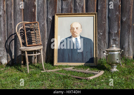 On grass, near wall of shed are standing outdated things Russian farmers rusted saw, wooden abacus, samovar, made with oil paints picture of Vladimir  Stock Photo