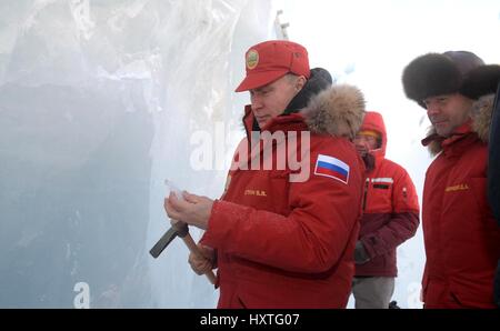 Alexandra Land, Russia. 29th Mar, 2017. Russian President Vladimir Putin chips off a piece of ice as Prime Minister Dmitry Medvedev, right, looks on during a visit to an ice cave in the Polar Aviators Glacier on Alexandra Land March 29, 2017 in Franz Josef Land archipelago, Russia. Putin is visiting the remote arctic islands to promote Russian claims to the regions natural resources. Credit: Planetpix/Alamy Live News Stock Photo