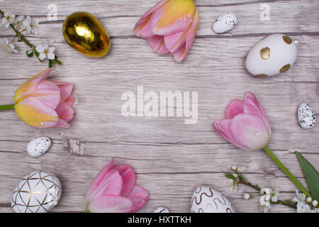 Easter eggs and tulips over wooden background. Stock Photo