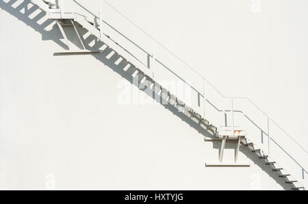 metallic staircase floating on an off-white wall background Stock Photo