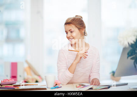 Smiling young illustrator looking away thoughtfully in search of inspiration to create lovely sketch for floral design magazine Stock Photo