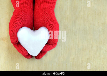 Snow heart in red gloves on wooden surface Stock Photo
