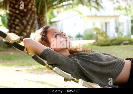 Side profile portrait of young woman lying in hammock outside house Stock Photo
