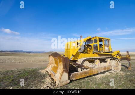 Yellow bulldozer in a field with blue sky. Stock Photo