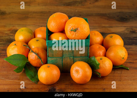 Tangerines in green basket on dark wooden background Stock Photo