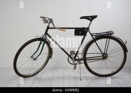 Old bike on white wooden floor and white textured wall Stock Photo