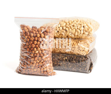 Dried fruits and nuts in transparent package over white: hazelnuts, cashew, roasted and salted peanuts, dried mulberry. Stock Photo