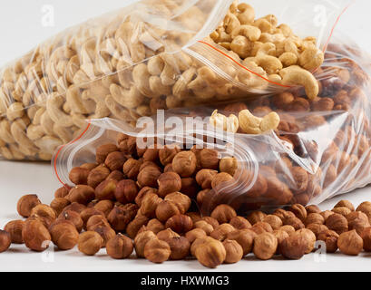 Closeup of cashew and hazelnuts in opened transparent zipper plastic bags over white Stock Photo