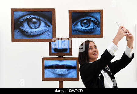 A visitor take a selfie in front of an installation during a press preview at the Selfie to Self-Expression exhibition at the Saatchi Gallery in London, which looks at the history of the selfie from portrait artists through to modern day selfies. Stock Photo