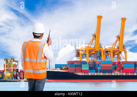 Dock worker talking on the walkie-talkie for controlling loading container in an industrial harbor Stock Photo