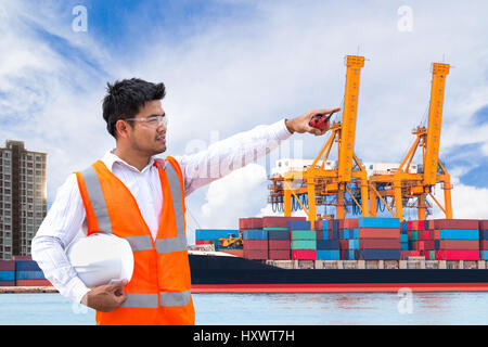 Port engineer standing in front of the industrial harbor with container cargo freight ship with working crane loading bridge in shipyard Stock Photo