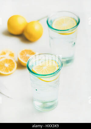 Morning detox lemon water in glasses served with fresh lemons over light grey marble background, selective focus. Clean eating, weight loss, healthy,  Stock Photo