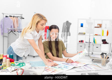 two young fashion designers collaborate on choosing color samples for a new clothing collection at the desk in the workshop Stock Photo