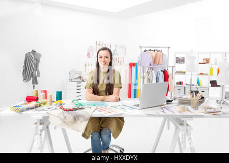 young saleswoman sitting at the desk in front of her laptop in the showroom Stock Photo
