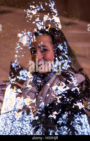 Double exposure of young woman in warm clothing smiling at camera and trees leaves Stock Photo