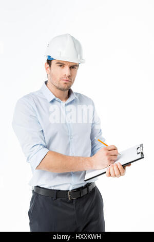 Confident male architect in hard hat making notes in clipboard Stock Photo