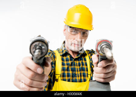 Close-up view of mature workman holding electric drills and looking at camera Stock Photo