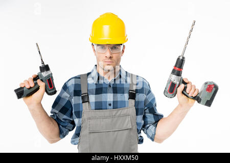 Serious workman in protective workwear holding electric drills Stock Photo