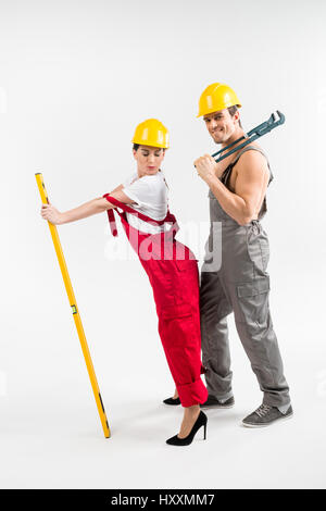 Young male and female builders posing with tools on grey Stock Photo