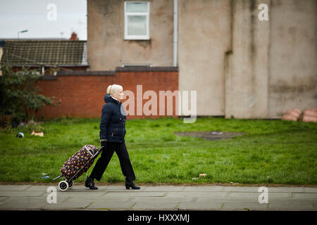 A mature lady pulling a shopping basket in Liverpool, England, UK. Stock Photo