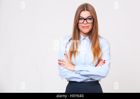 Portrait of beautiful happy young business woman standing against gray background. Stock Photo