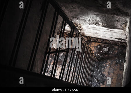 Old empty abandoned bunker interior with rusted metal ladder going down from dark room to the light Stock Photo