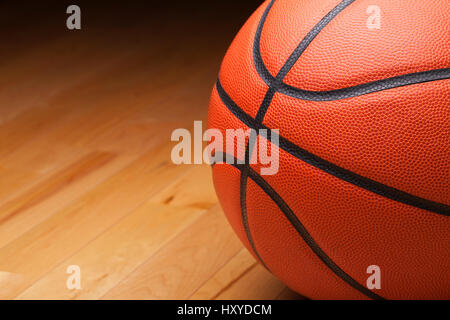 Close up shot of a basketball on a hardwood gym floor Stock Photo