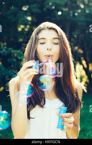 Beautiful young woman blowing bubbles outdoors Stock Photo