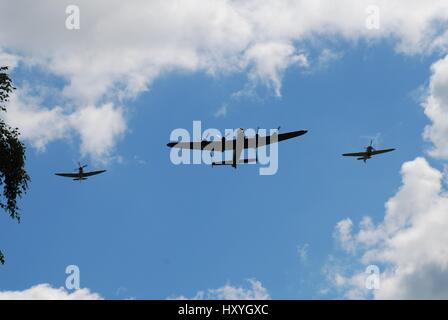The Battle of Britain Memorial Flight, comprising a Lancaster bomber flanked by Spitfire and Hurricane fighters, displays over Tenterden, England. Stock Photo