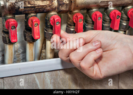 Home water distribution manifold system, valves blocking access to water pipes, close-up human hand opened valve on pipe. Stock Photo
