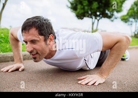 Mid adult man doing pushups outdoors Stock Photo