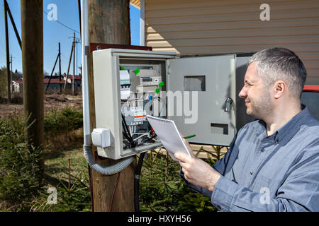 Country electrician engineer inspecting electric counter equipment in distribution fuse box. Stock Photo