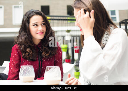 Young cute women talking while having a coffee outdoors Stock Photo