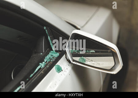 Close up of a broken window and passenger-side mirror on a modern, white sports car parked in a garage. Stock Photo
