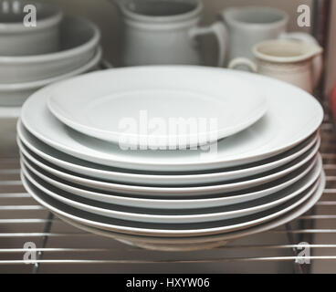 Dishes stacked on shelves in a kitchen area. Stock Photo