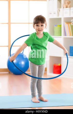 kid girl doing gymnastic with hoop in children room at home Stock Photo