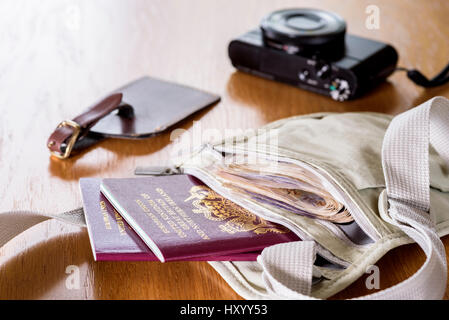 Money belt laid out on a table, with currency,  passports, camera and luggage tag. Stock Photo