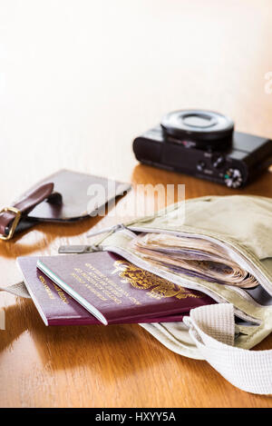 Money belt laid out on a table, with currency,  passports, camera and luggage tag. Stock Photo