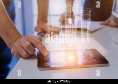 Team of architects discussing 3d building project sketch or blueprint with hologram technology and digital tablet Stock Photo