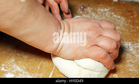 Baker kneading dough with hand on table in flour Stock Photo