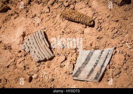 Two potsherds (or Pot shards) and a dried cob from maize grown in Southern Utah long ago rest in the sand near some ancients pueblo dwellings. Stock Photo