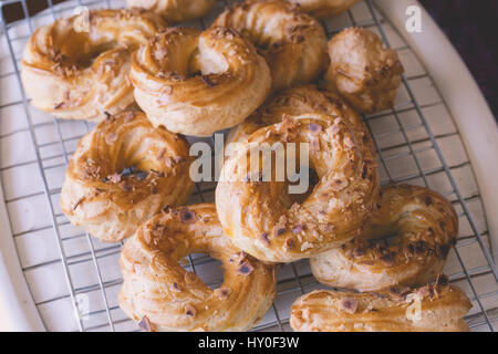 Freshly baked delicious profiteroles covered with roasted almonds cooling down on a plate. French dessert. Stock Photo