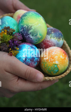 Toddlers hands holding easter eggs in basket Stock Photo