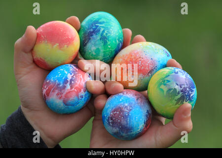 Toddlers hands holding easter colored eggs Stock Photo