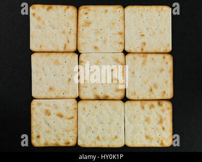 Pattern of Dry Cream Crackers Against a Black Background Stock Photo