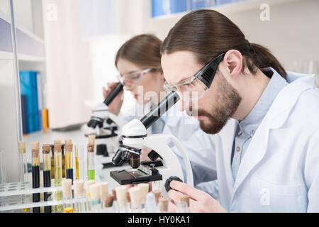 Young male and female scientists working with microscopes in laboratory Stock Photo