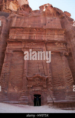 Jordan: a man and a red tomb along the Street of Facades, row of monumental Nabataean tombs carved in the archaeological Nabataean city of Petra Stock Photo